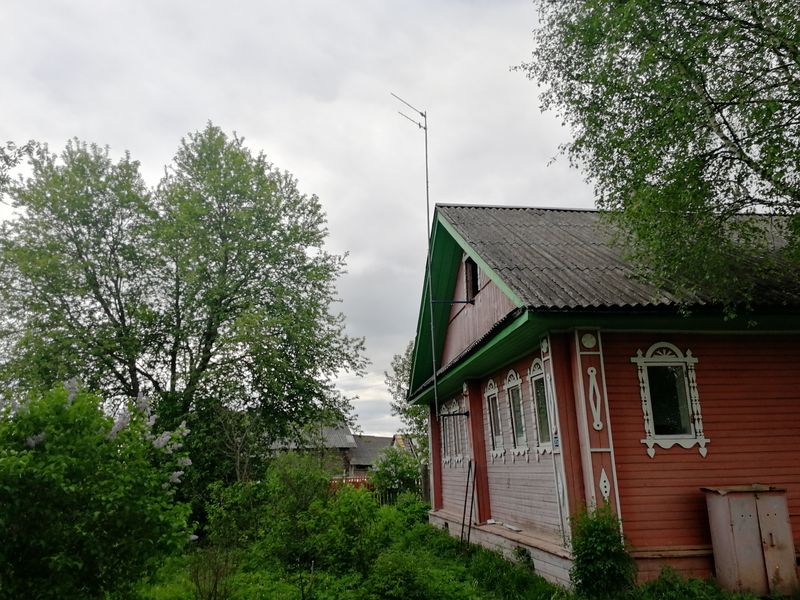 Антенна на мачте над крышей красного деревянного дома