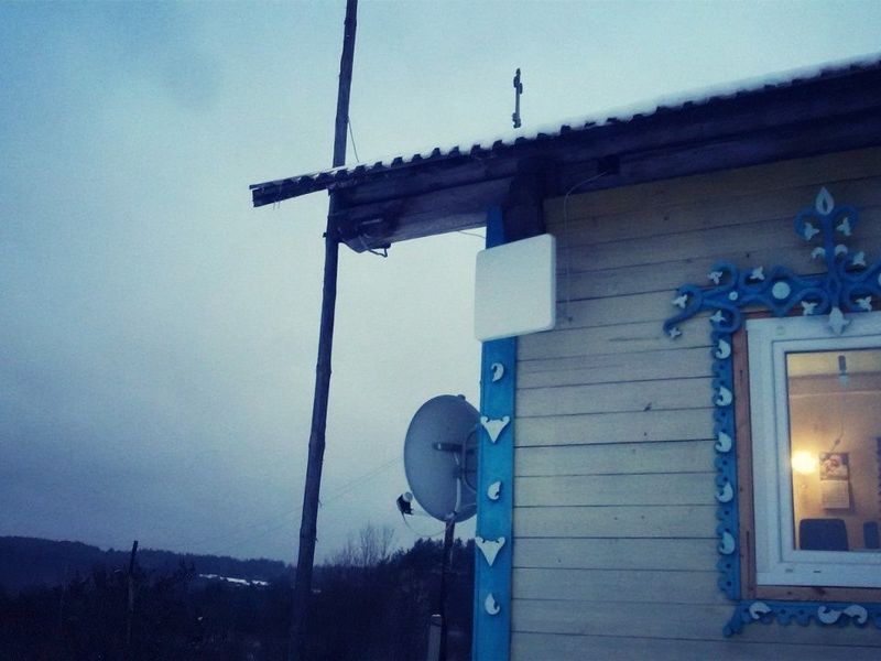 Панельная антенна на кронштейне на углу дома зимой